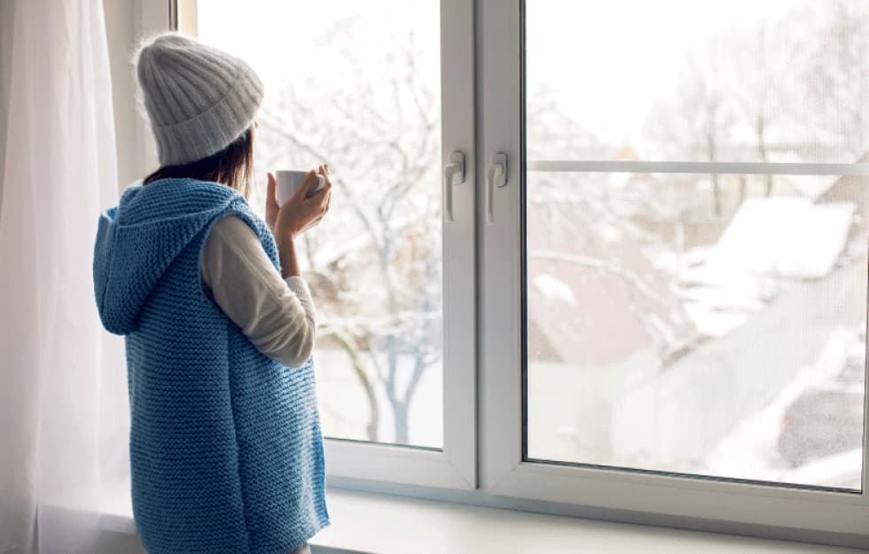 Woman looking out a snowy window