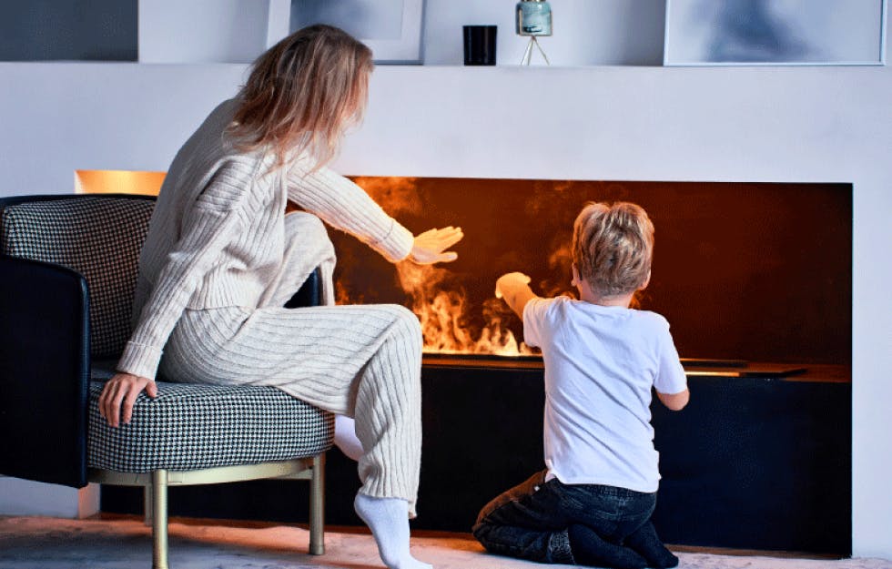 Woman and child warming their hands at an electric fireplace